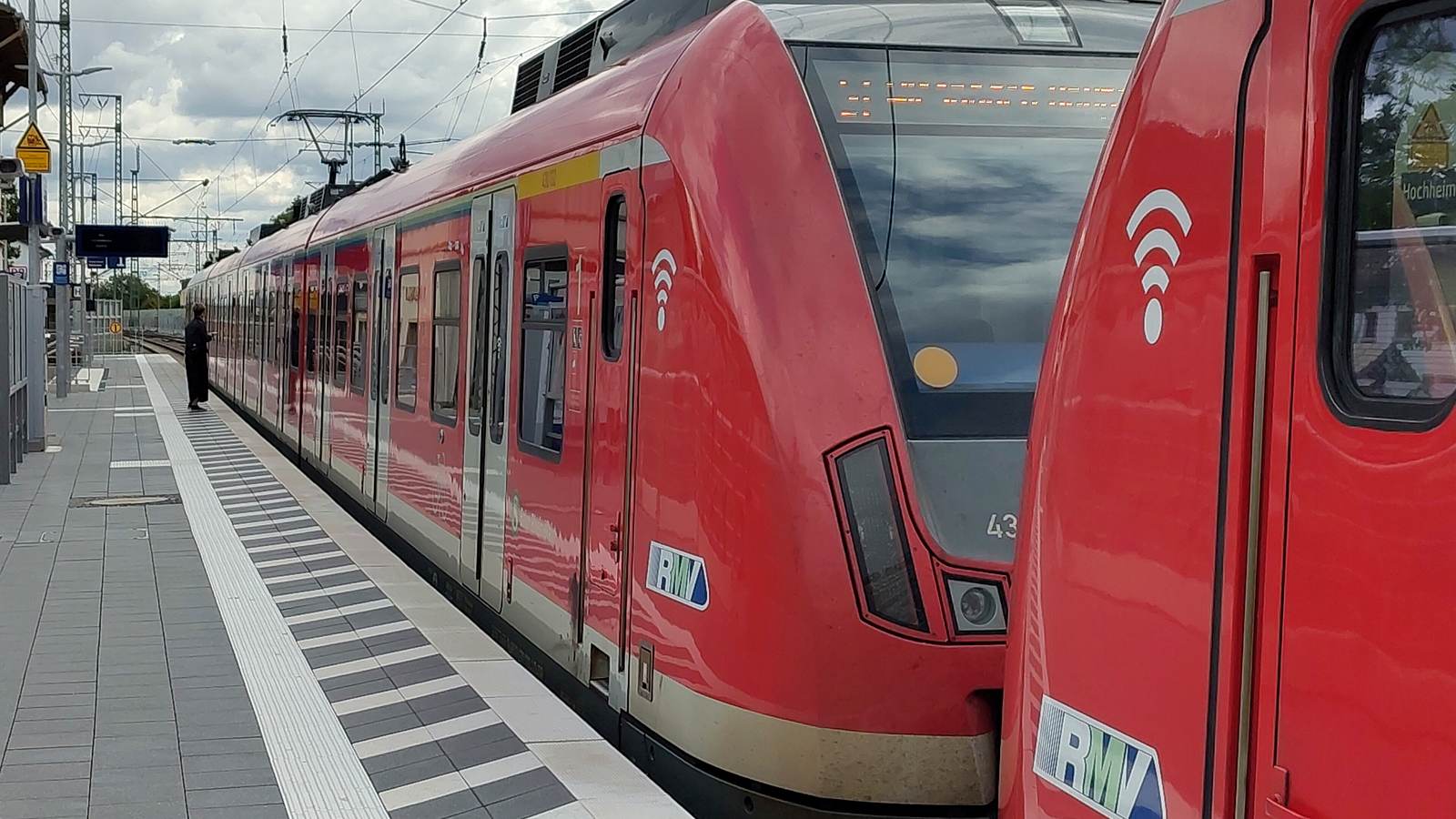 Zwei rote S-Bahn-Triebzüge der S-Bahn Rhein-Main mit RMV-Logo am neuen, erhöhten Bahnsteig des Bahnhofs Hochheim (Main), auf dem Bahnsteig taktile Leitstreifen
